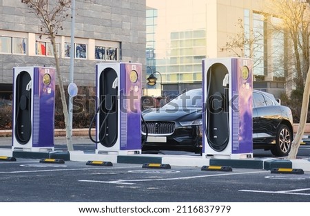 Electric car charging station with EV car parked and refueling Royalty-Free Stock Photo #2116837979