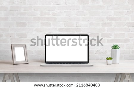 Laptop mockup on work desk. Work at home concept. Clean desk with photo frame and plants