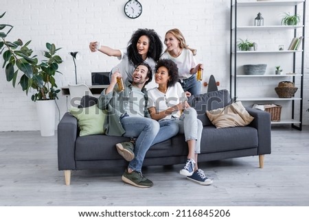 happy african american woman taking selfie with friends in living room