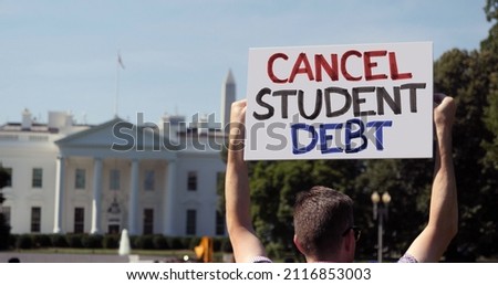A man holds an CANCEL STUDENT DEBT protest sign in front of the White House on a sunny summer day. Student debt was a hot topic during the COVID-19 pandemic.	 Royalty-Free Stock Photo #2116853003