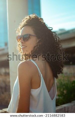 An attractive smiling Hispanic female in sunglasses