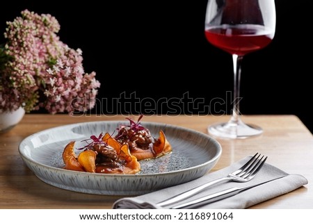 beef with sauce and sweet potato on a restaurant table with a glass of wine close up. restaurant dinner with dark background. photo