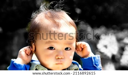 Baby touching his ears isolated on a black background and copy space and outdoors.?or hear no evil
