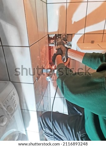 Plumber cutting old water pipe in the bathroom by angle grinder , plumbing concept.
