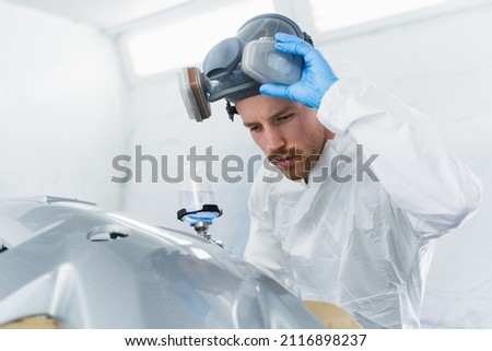 Young male car painter checks the quality of painting. Car service worker at work Royalty-Free Stock Photo #2116898237