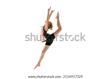 High jump, flight. Little flexible girl, rhythmic gymnastics artist jumping isolated on white background. Grace in motion, action. Doing exercises in flexibility. Beauty, sport, challenges, studying Royalty-Free Stock Photo #2116917329