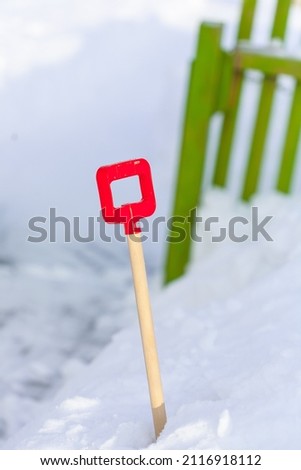 Close up of little red plastic showel in the process of removing the snow in winter