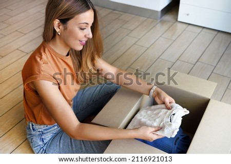 Second hand clothes. Beautiful young woman preparing donation box with clothing. Royalty-Free Stock Photo #2116921013