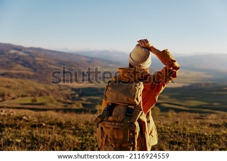 woman traveler in a yellow jacket in a hat backpack travel mountains Lifestyle Royalty-Free Stock Photo #2116924559