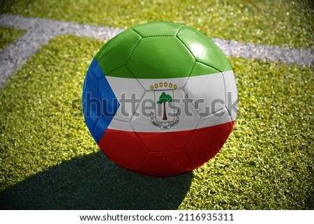 football ball with the national flag of equatorial guinea lies on the green field near the white line