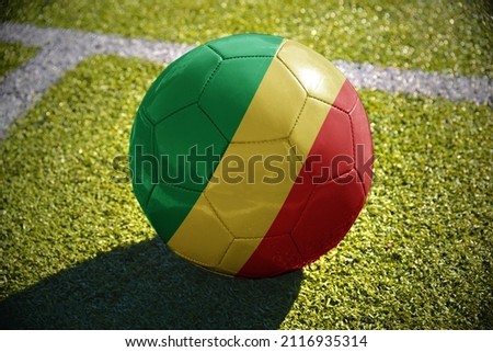 football ball with the national flag of republic of the congo lies on the green field near the white line