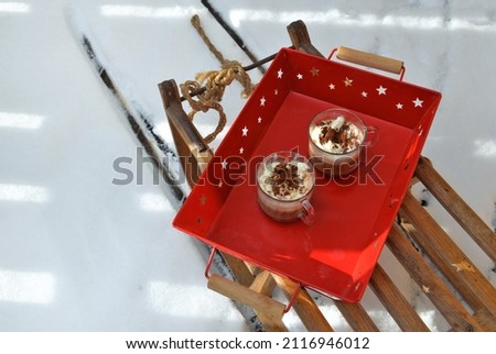 cups of cappuccino placed in a red tray on a wooden sled in the  snow