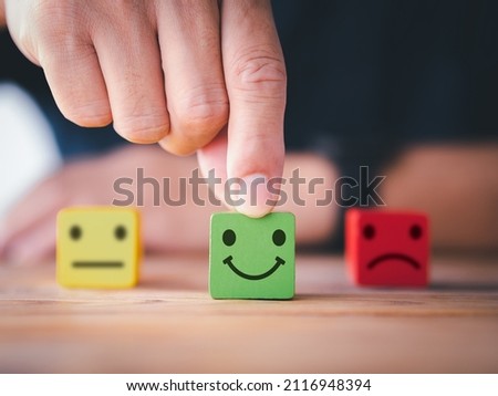 Customer satisfaction survey concept. Close up customer hand choose happy smiley face, blurred neutral and sad face icon on wood cube to survey feedback, rating, review, service satisfaction. Royalty-Free Stock Photo #2116948394