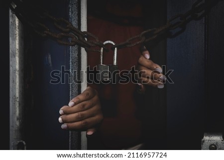 Unidentified woman's hand trapped in an illegally smuggled container locked with chain and key. Efforts to escape from the confinement were tortured : Human Trafficking and Illegal Immigration. Royalty-Free Stock Photo #2116957724