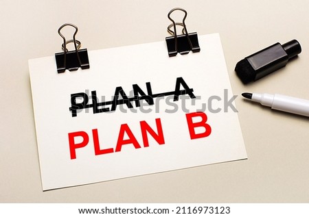 On a light background, a black open marker and on black clips a white sheet of paper with the text PLAN B