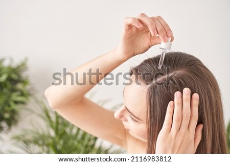Young woman hair treatment. Argan oil healthy massage. Morning bathroom routine. Female person applying transparent keratin mask product. Liquid cosmetic dropper therapy. Royalty-Free Stock Photo #2116983812