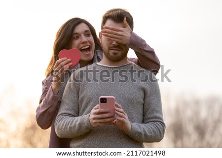 Young couple celebrating valentine's day giving a gift on a park
