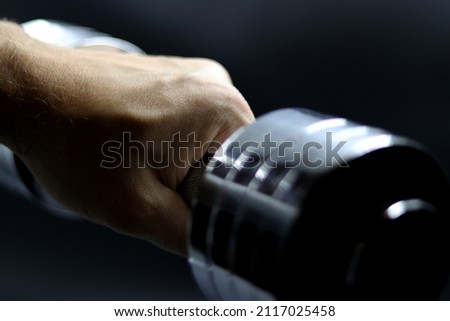 Hand holding a dumbbell with a black background