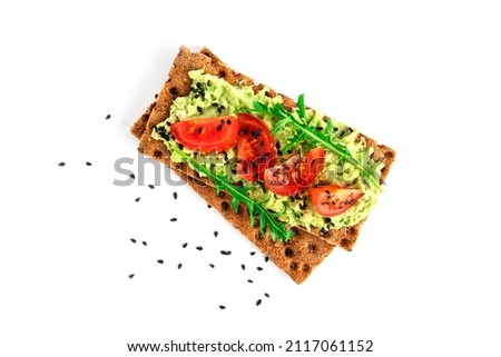 Avocado sandwich with avocado cream and rye crisp bread for snack. Fiber, fitness and diet food. Rye bread with guacamole, arugula and cherry tomatoes isolated on a white background.  Royalty-Free Stock Photo #2117061152