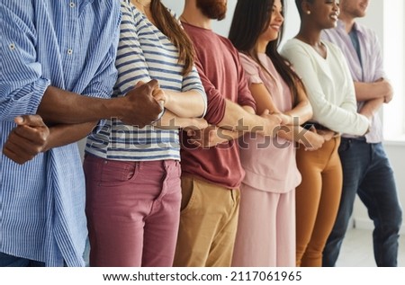 Diverse team of different happy young people standing together. Multiethnic group of good friends standing in a row, holding hands and smiling. Teamwork, unity and diversity concepts Royalty-Free Stock Photo #2117061965