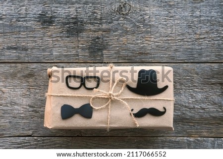 Happy Fathers Day concept.  Gift box wrapped craft paper black glasses and mustache sign on the wooden background. Fathers Day sale promotion poster design Blank copy space for lettering. February 23.