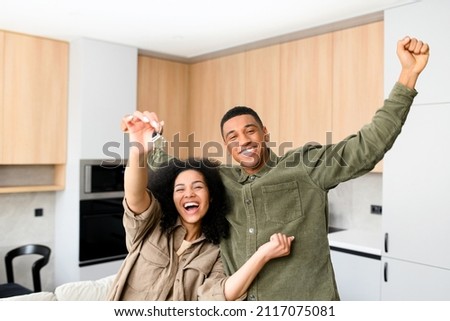 Multiracial couple in love hugging in a new home while holding keys in hands. Young multiracial family bought a new house, rent an apartment, got a mortgage Royalty-Free Stock Photo #2117075081