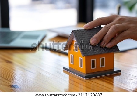 Real estate broker agent presenting and consult to the customer to decision making sign insurance form agreement, home model, concerning mortgage loan offer for and house insurance