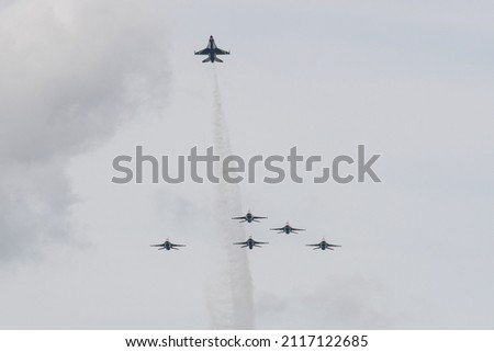 A view of a herd of General Dynamics F-16 Fighting Falcon planes flying high in the gray sky Royalty-Free Stock Photo #2117122685