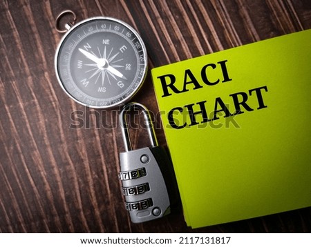 Top view compass,padlock and colored note with text RACI CHART on wooden background. Royalty-Free Stock Photo #2117131817