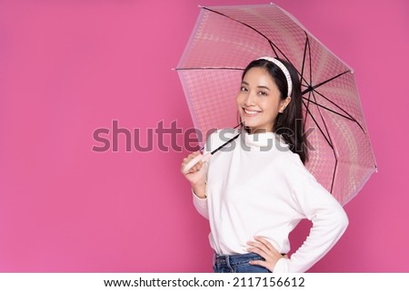 Portrait Asian beautiful happy young woman smiling cheerful and holding umbrella isolated on pink studio background