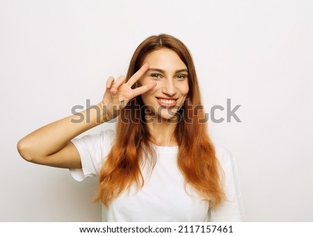 cheerful excited woman with long red hair showing peace sign Royalty-Free Stock Photo #2117157461