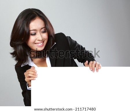 Portrait of beautiful businesswoman holding blank billboard on grey background