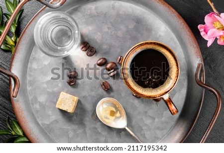 Espresso in a cup on a tray with a glass of water and sugar. View from above. Aromatic Italian coffee for breakfast in a cafe.