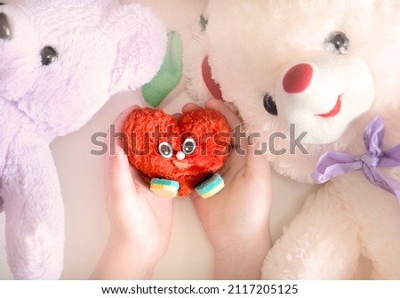 Child holding handmade soft heart, cute craft for Valentines day or birthday. DIY