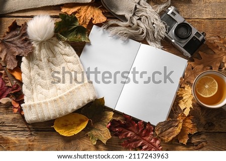 Blank book, cup of tea, photo camera and autumn decor on wooden background