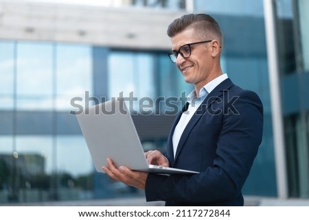 Business. Businessman Using Laptop Outdoor Adult Caucasian Male Business Person Eyeglasses Watching Notebook Screen Outside Smiling Happy Positive Emotions Background Big City Street