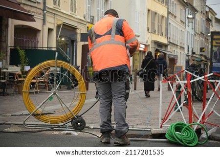 technician who installs optical fiber in the city center in France Royalty-Free Stock Photo #2117281535