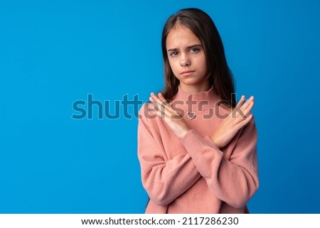Young beautiful teen girl crossing arms doing negative sign on blue background
