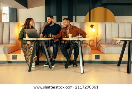 Modern entrepreneurs working together in a lobby. Team of happy businesspeople smiling while having a discussion. Group of entrepreneurs collaborating on a new project in a co-working space. Royalty-Free Stock Photo #2117290361