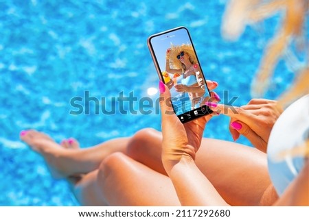 Woman using video sharing social media app on mobile phone while sitting by the pool