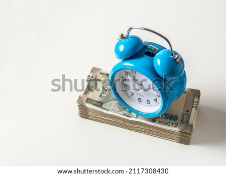A vintage alarm clock placed on a stack of five hundred Indian rupee notes. A concept for ‘fix deposit’ or ‘long term investment’. Royalty-Free Stock Photo #2117308430