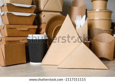 Containers for pizza and sandwich made of triangular paper on the background of disposable tableware. The concept of using paper packaging for fast food.