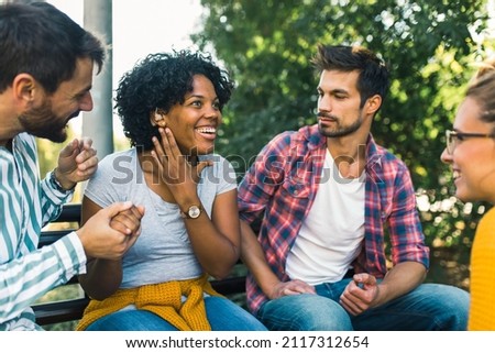 Woman with ear hearing problem having fun with her friends in the park Royalty-Free Stock Photo #2117312654