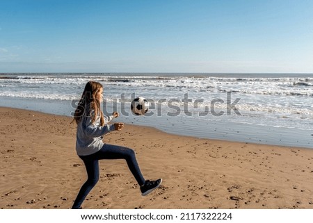 A view of the young female playing football on the beach