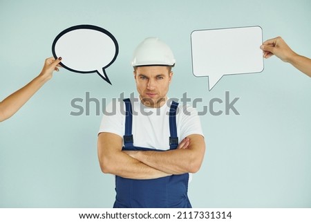 Worker is thinking. Man standing in the studio with empty signs for the text.