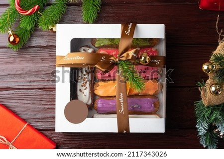 Box of colorful eclairs on Christmas background, close up