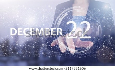 December 22nd. Day 22 of month, Calendar date. Hand click luminous hologram calendar date on light blue town background. Winter month, day of the year concept