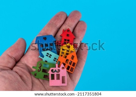 Several wooden symbolic houses lie in a male palm on a blue background