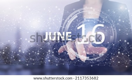 June 16th. Day 16 of month, Calendar date. Hand click luminous hologram calendar date on light blue town background. Summer month, day of the year concept