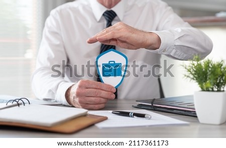 Concept of job loss insurance with paper shield protected by hand of insurer Royalty-Free Stock Photo #2117361173
